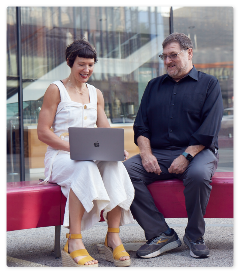 Alia and Mark, smiling and looking at a laptop